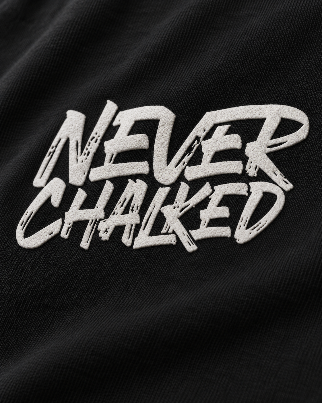 Detail visualization of the raised white Never Chalked puff-print front graphic on black cotton.