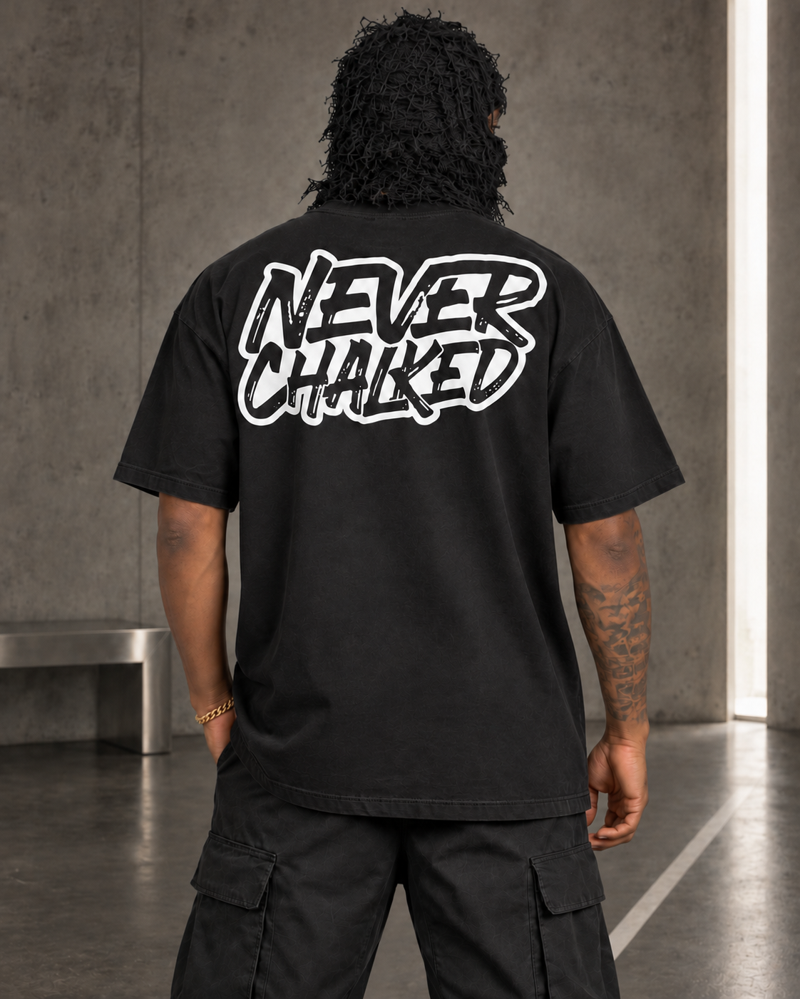 Back view of the black Never Chalked Classic Heavyweight Tee with large white screen-printed artwork, styled in the Next Move set.
